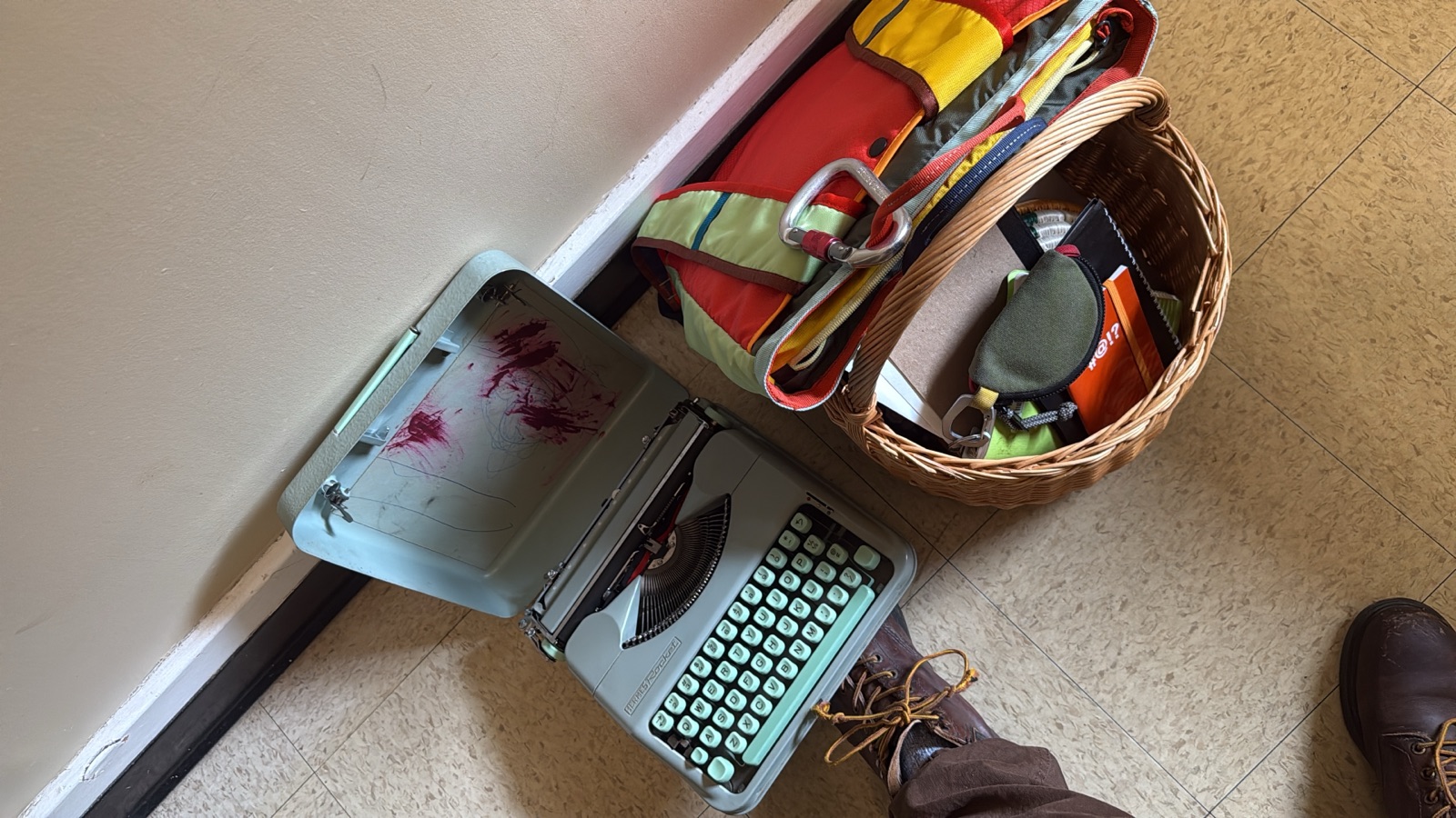 A pale green portable typewriter in its open case on a classroom floor.